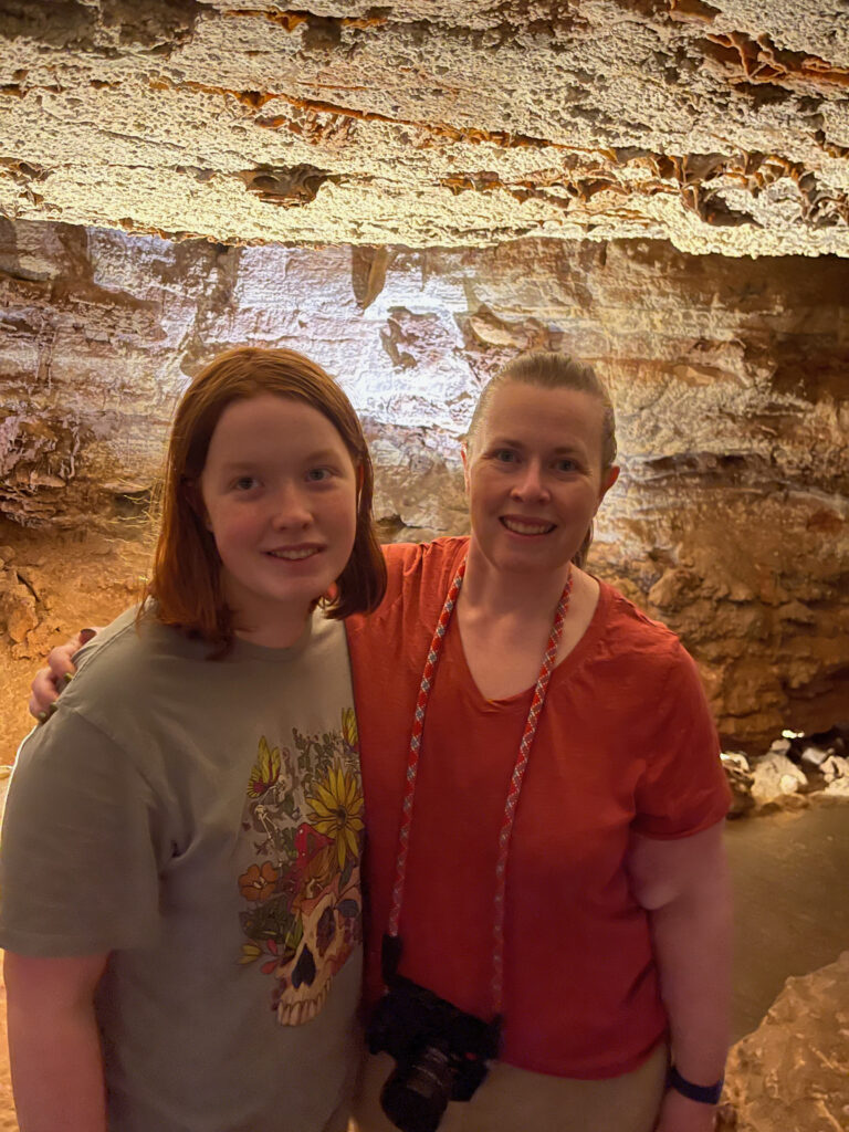 Cat and Cameron pose for a photo on the cave tour at Wind Cave National Park. Cat has a camera strapped around her neck.