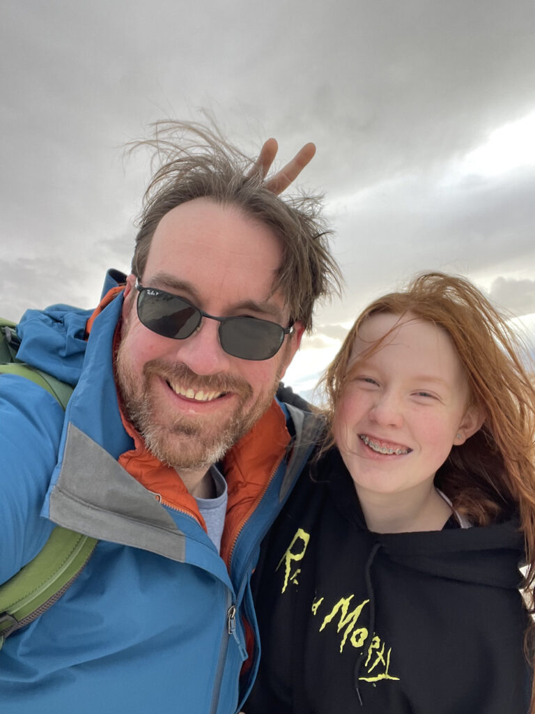 A close up photo of both Cameron and myself, all smiles and wind blown hair. Taken way out on the dunes of White Stands with storm clouds over our head. 