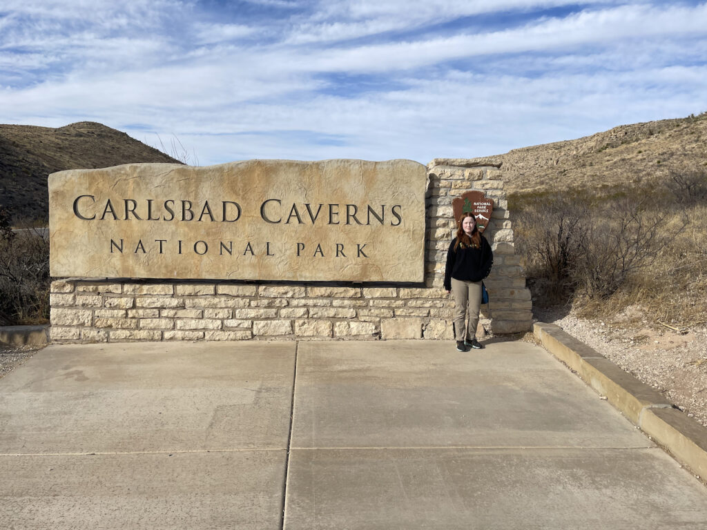 Cameron standing in front of the Carlsbad Caverns National Park sign.