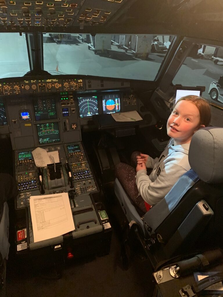 Cameron sitting in the First Officers chair in the cockpit of a JetBlue A321 airplane.