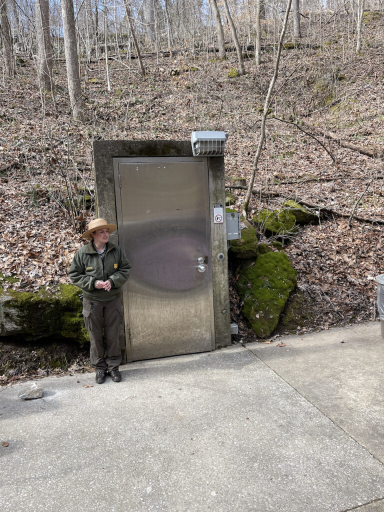 A ranger giving a talk before our cave tour at Mammoth. The massive steel door is at the base of a large hill.