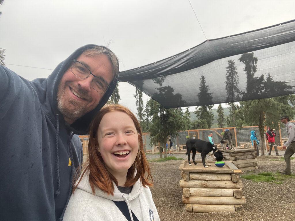 Cami and I standing in front of the sled dogs that are standing on top of their houses in Denali.