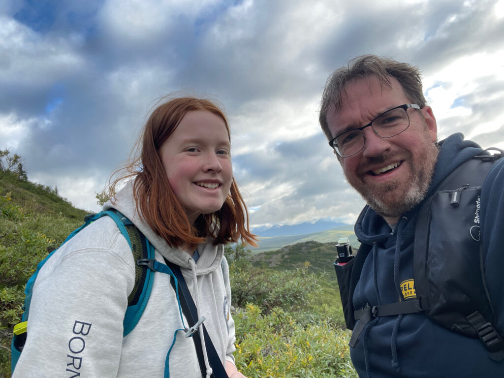 Cameron and I taking a break hiking up the Savage Alpine Trail in Denali - with views of mountains and rivers behind us.