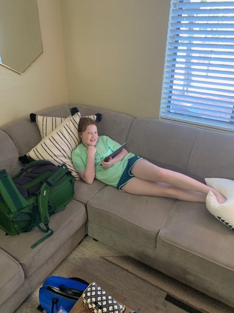 Cameron laying on a sofa with her Ipad in an AirBnB in Sedona. 