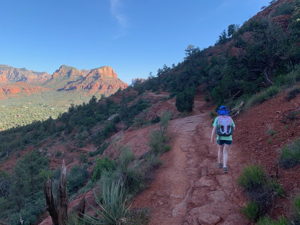 Cameron hiking on Badwin Trail in Sedona at sunset with a view of Cathedral Rock in the background.