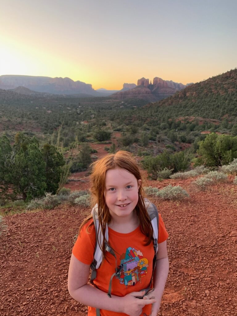 Cameron hiking on Badwin Trail in Sedona at sunset with a view of Cathedral Rock in the background.