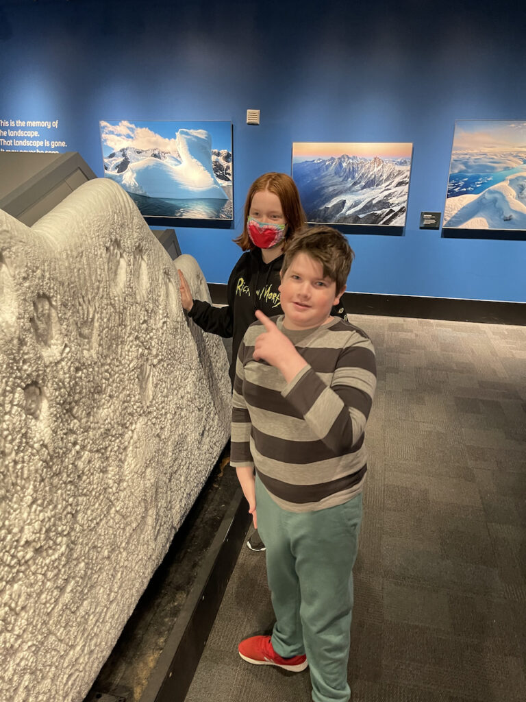 Cameron and Collin touching a frozen wall of ice and snow inside the Museum of Science and Industry. 