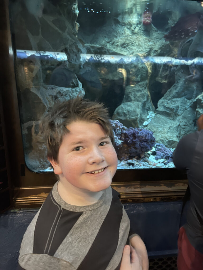 Collin smiling in front of a fish take at the Shedd Aquarium.