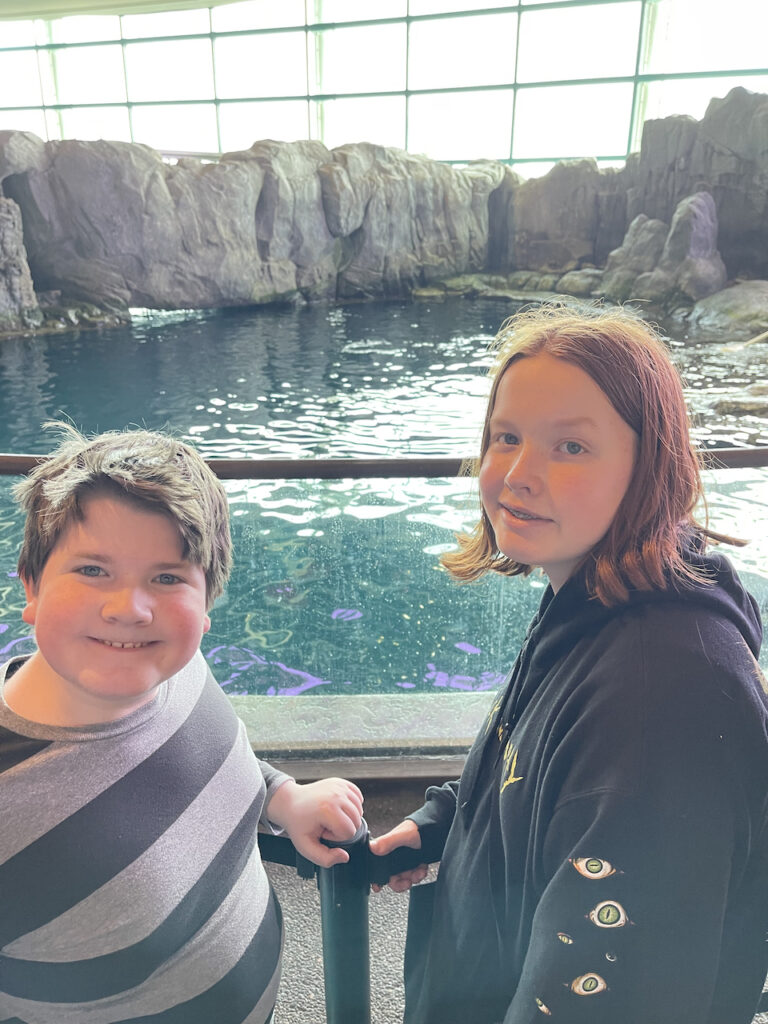 Collin and Cameron smiling in front of a giant tank at the Shedd Aquarium.