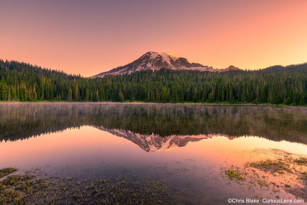 Reflection Lakes in Mount Rainier National Park with a clear view of Mount Rainier, perfect reflection, and early morning fog on the water.