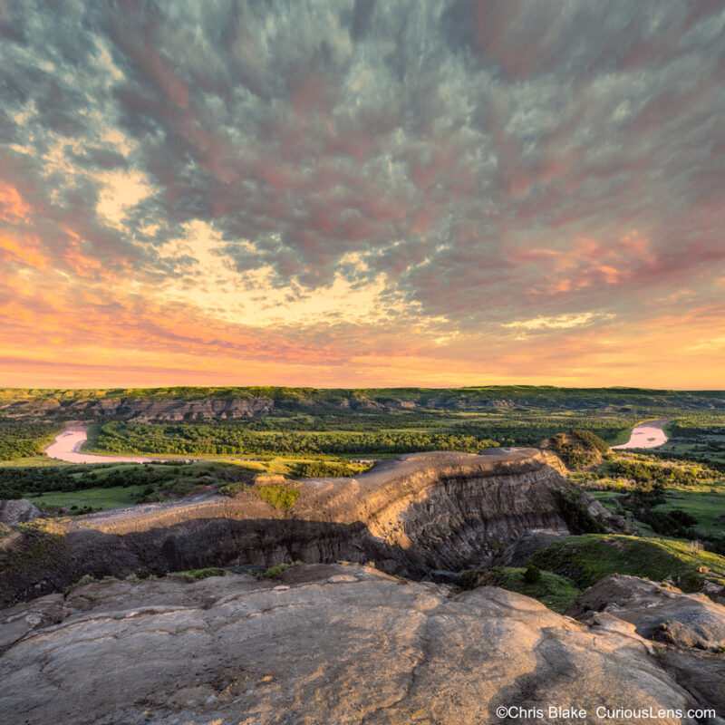 Oxbow Bend in the Northern Unit of Theodore Roosevelt National Park at sunset with colorful clouds reflecting in the Little Missouri River after a storm.