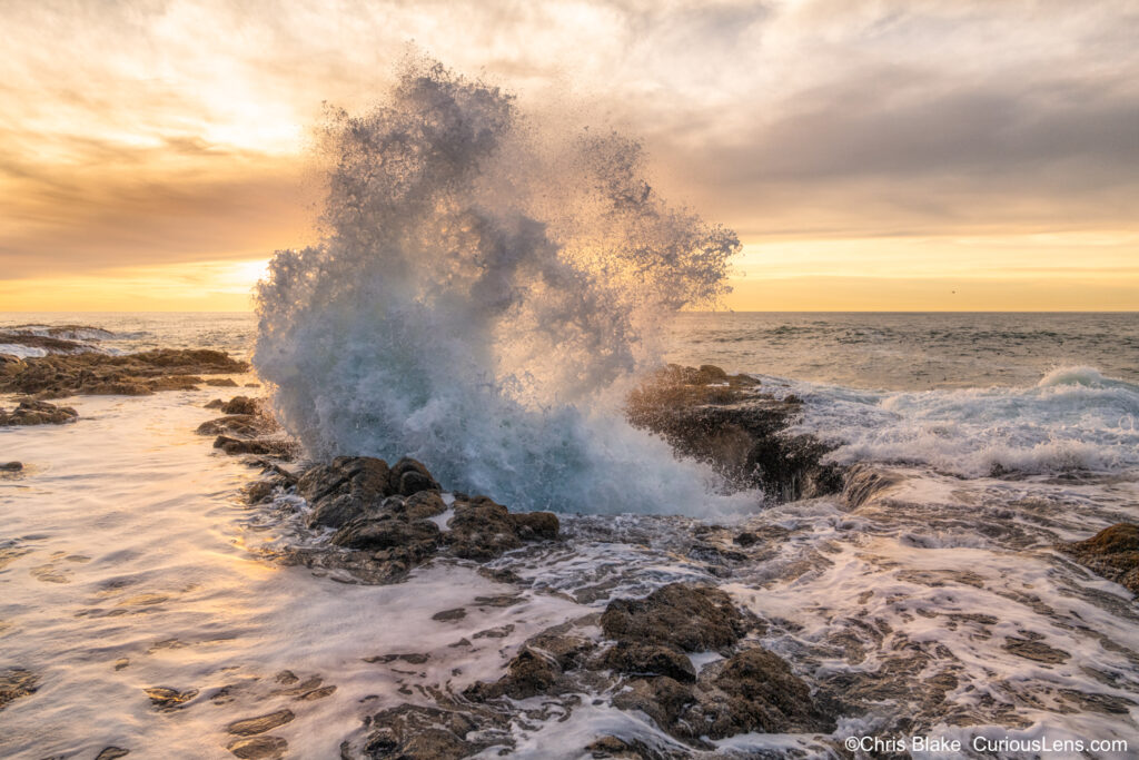 Thor’s Well near Cape Perpetua, Oregon coast, at high tide with powerful geysers, vibrant sunset colors, and water reflecting the warm hues.