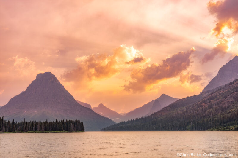 Sunset at Two Medicine Valley in Glacier National Park with smoky skies, storm clouds, light rays, and dramatic colors over the lake.