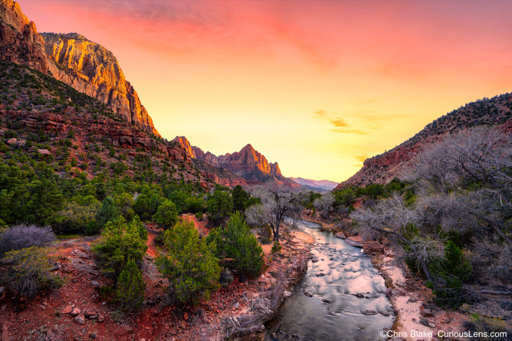 Winter evening at The Watchman in Zion National Park with red and yellow sky, glowing rocks, and river reflection.