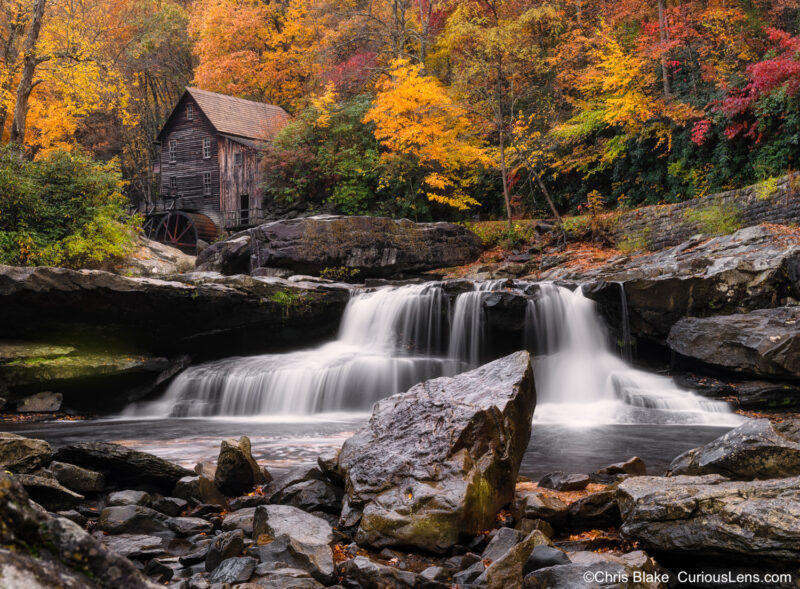 Glade Creek Grist Mill in Babcock State Park surrounded by peak fall foliage, rushing river, and vibrant colors in the rain.