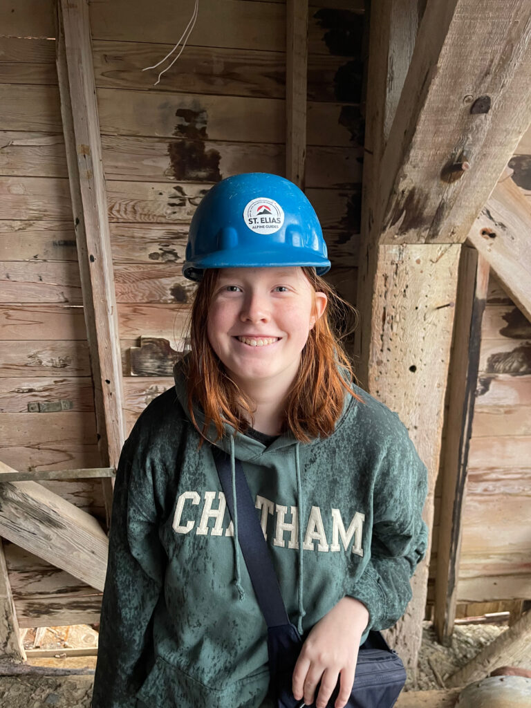 Cameron wearing a hard hat standing inside at the top of the Mill Building inside of Kennicott. 