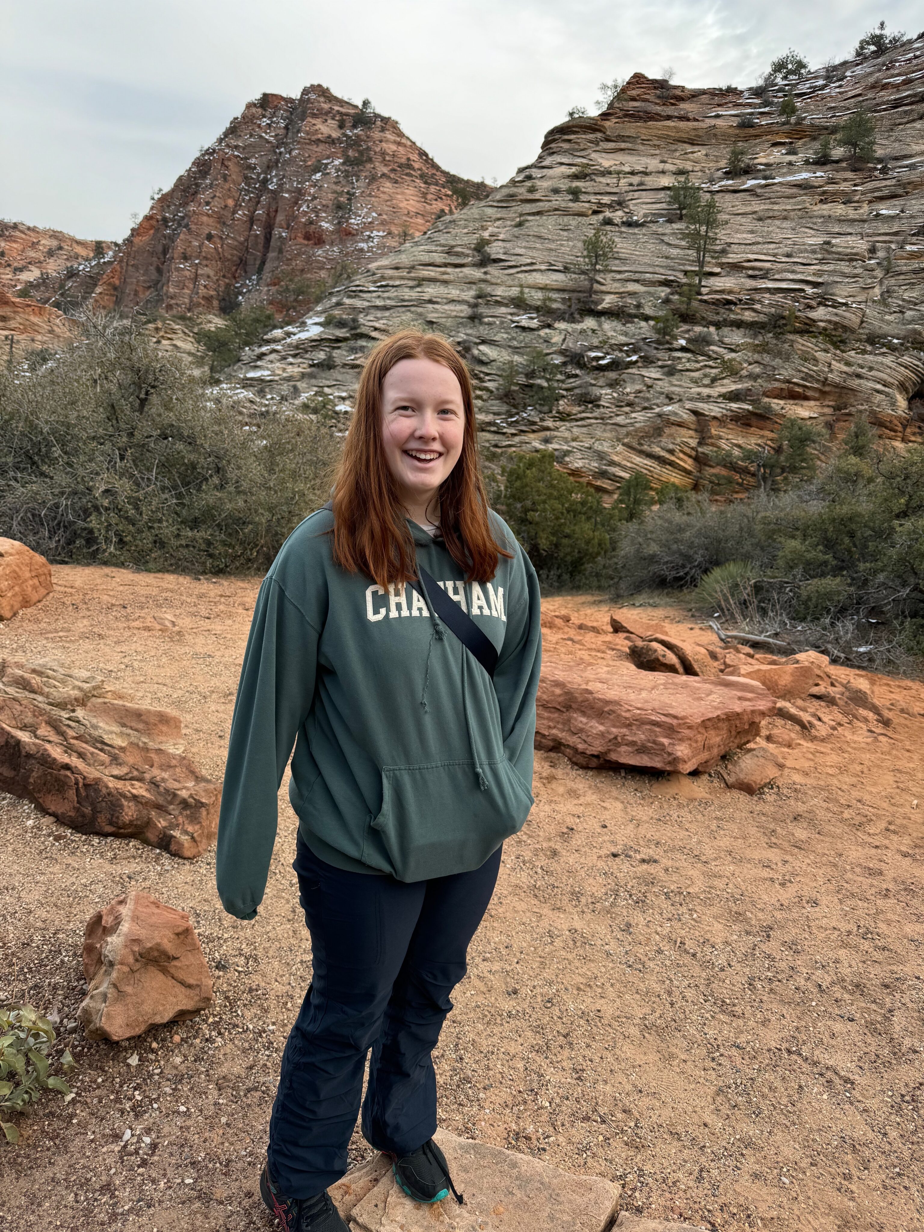 Cameron standing with a big smile on her face at the top of a short hike on the east side of Zion off the Mount Carmel Highway.