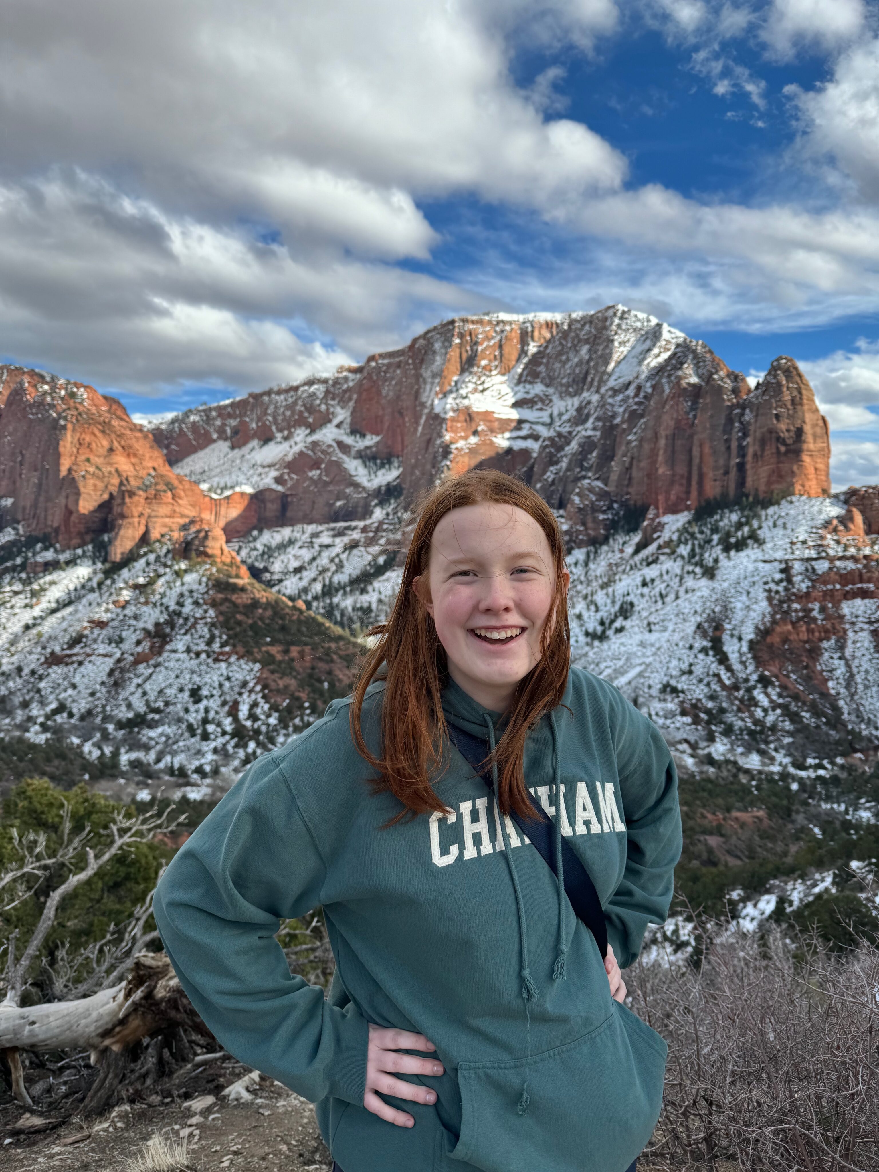 Cameron stands and poses for a photo with snow covered sandstone mountains in the background in the Kolob Canyon areas of Zion.