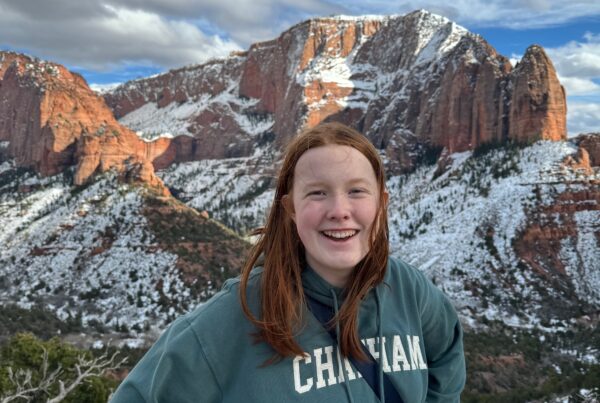 Cameron stands and poses for a photo with snow covered sandstone mountains in the background in the Kolob Canyon areas of Zion.