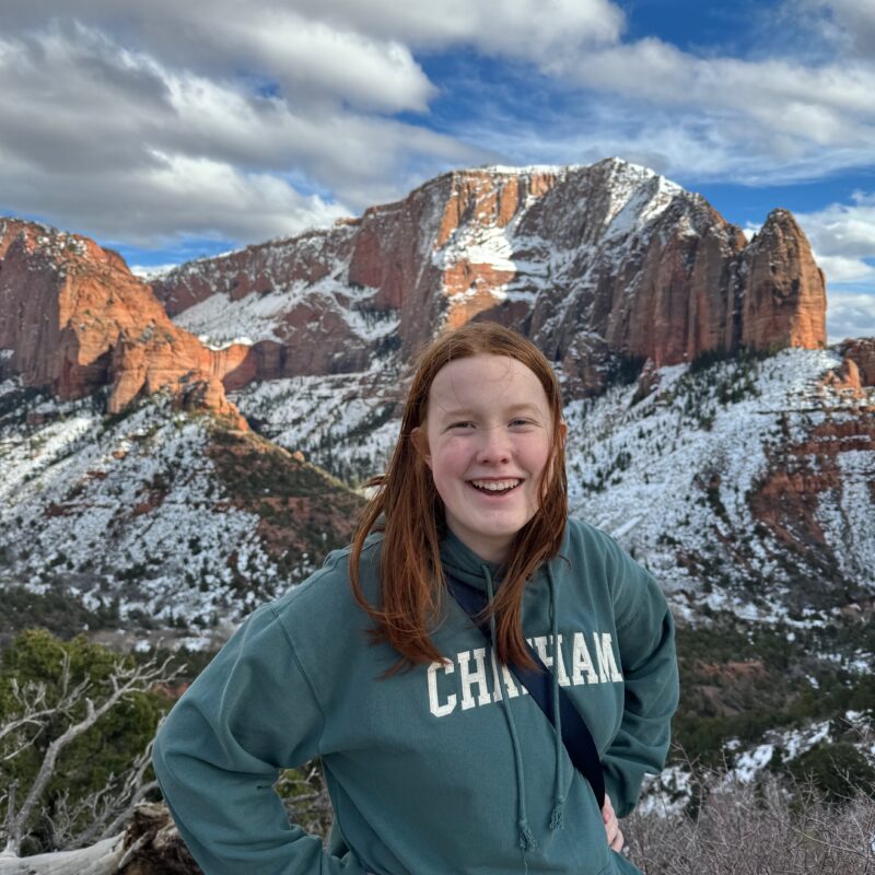 Cameron stands and poses for a photo with snow covered sandstone mountains in the background in the Kolob Canyon areas of Zion.