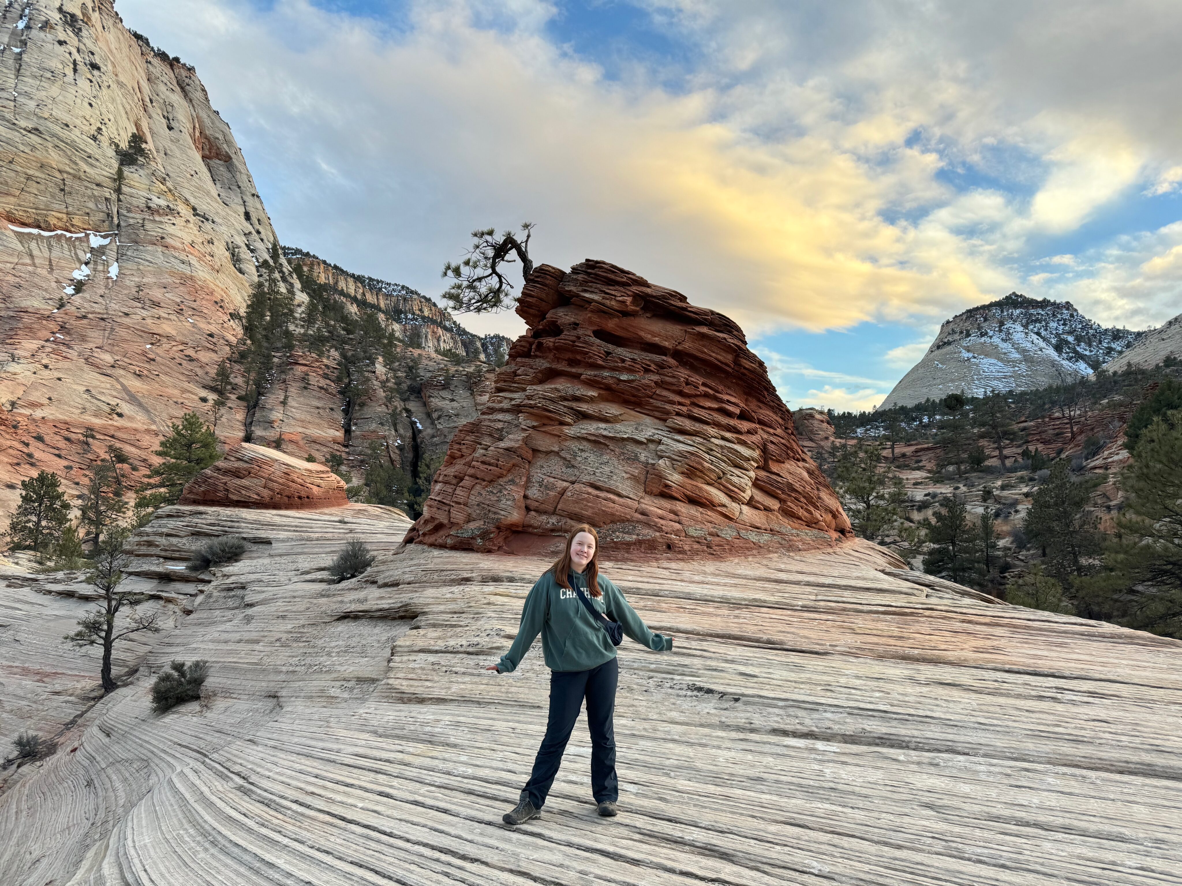 Cameron poses at sunset near a strange rock formation we found while hiking on the East Side of Zion National Park. White and Yellow clouds are overhead as the last light of day hits them.