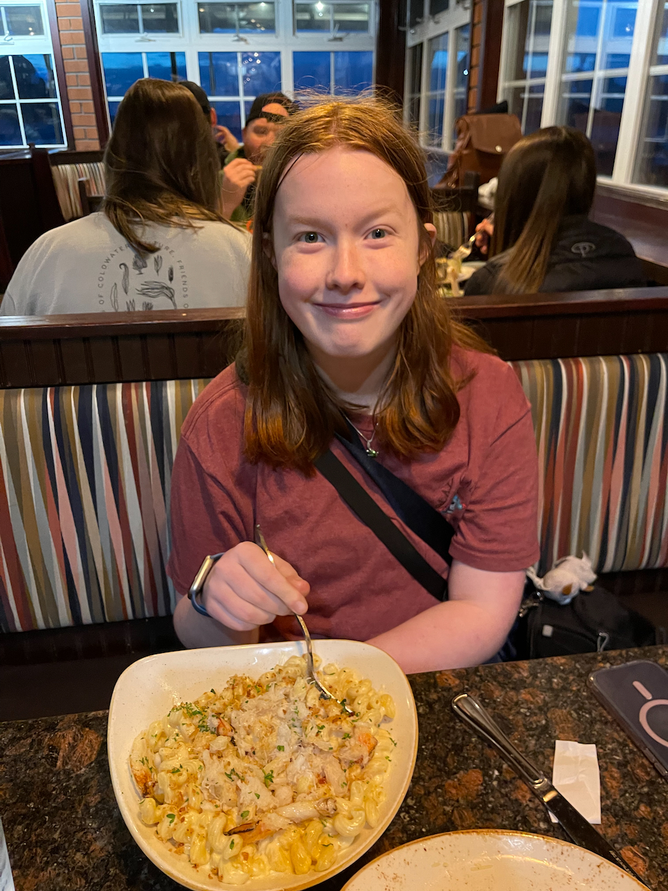 Cameron sitting in a booth at the Pelican Brewing Co with a massive bowl of crab mac-n-cheese in front of her. 