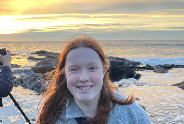 Cameron with a big smile, her red hair glowing for the yellow stunning sunset taking place behind her. You can also see part of my cameras tripod setup to capture Thors Well and the amazing sunset.