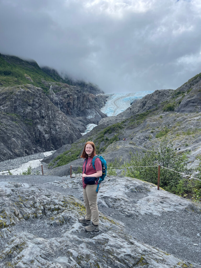 Cameron nearing the end of the Exit Glacier trail, a rope to keep you on the trail can be seen, the glacier and the river that runs off of it can be seen in the distance. 