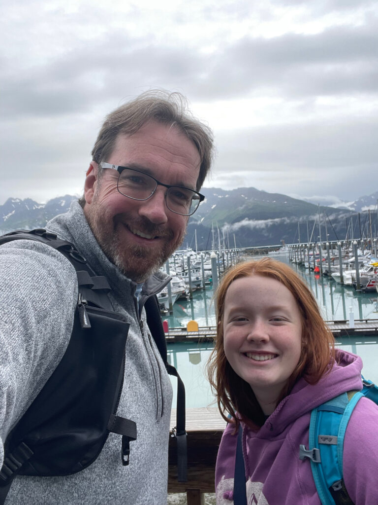 Cameron and myself pose for a photo on the raised boardwalk near all the boats in Seward Alaska. About to head off on a stormy day to tour the coastal glaciers of Kenai Fjords. 