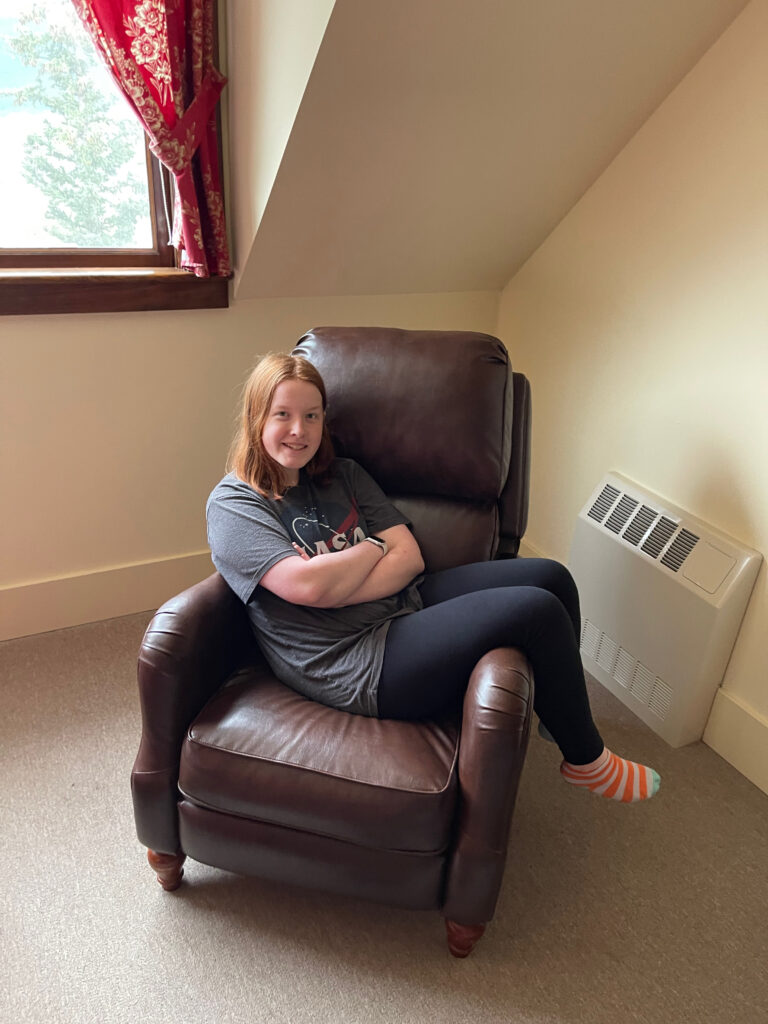 Cameron sitting sideways in a large leather arm chair inside our hotel room in the Kennicott Glacier Lodge. 