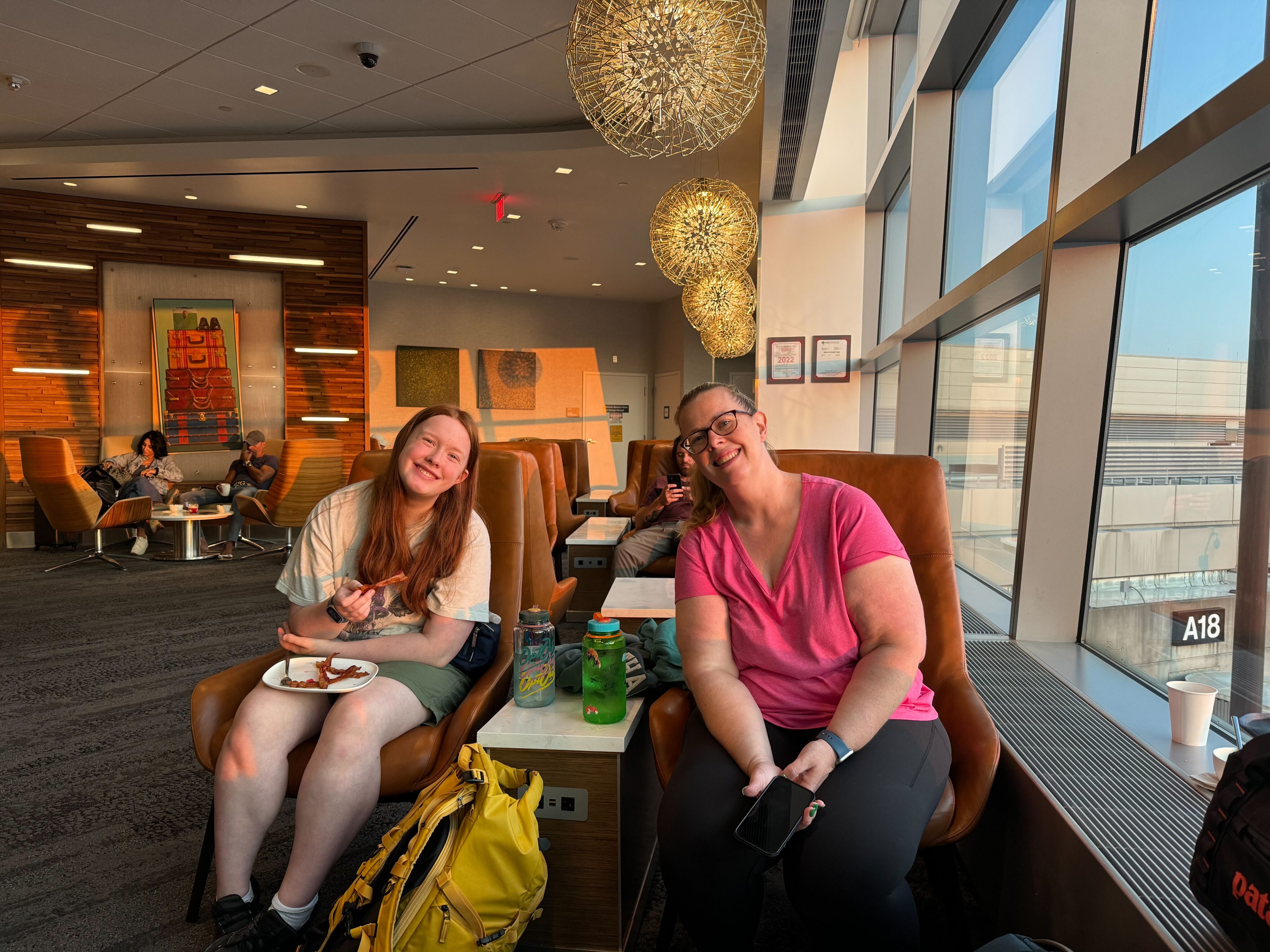 Cat and Cami sitting in the Delta Lounge by the windows at Logan Airport. Taken right after sunrise with the first morning light coming in.