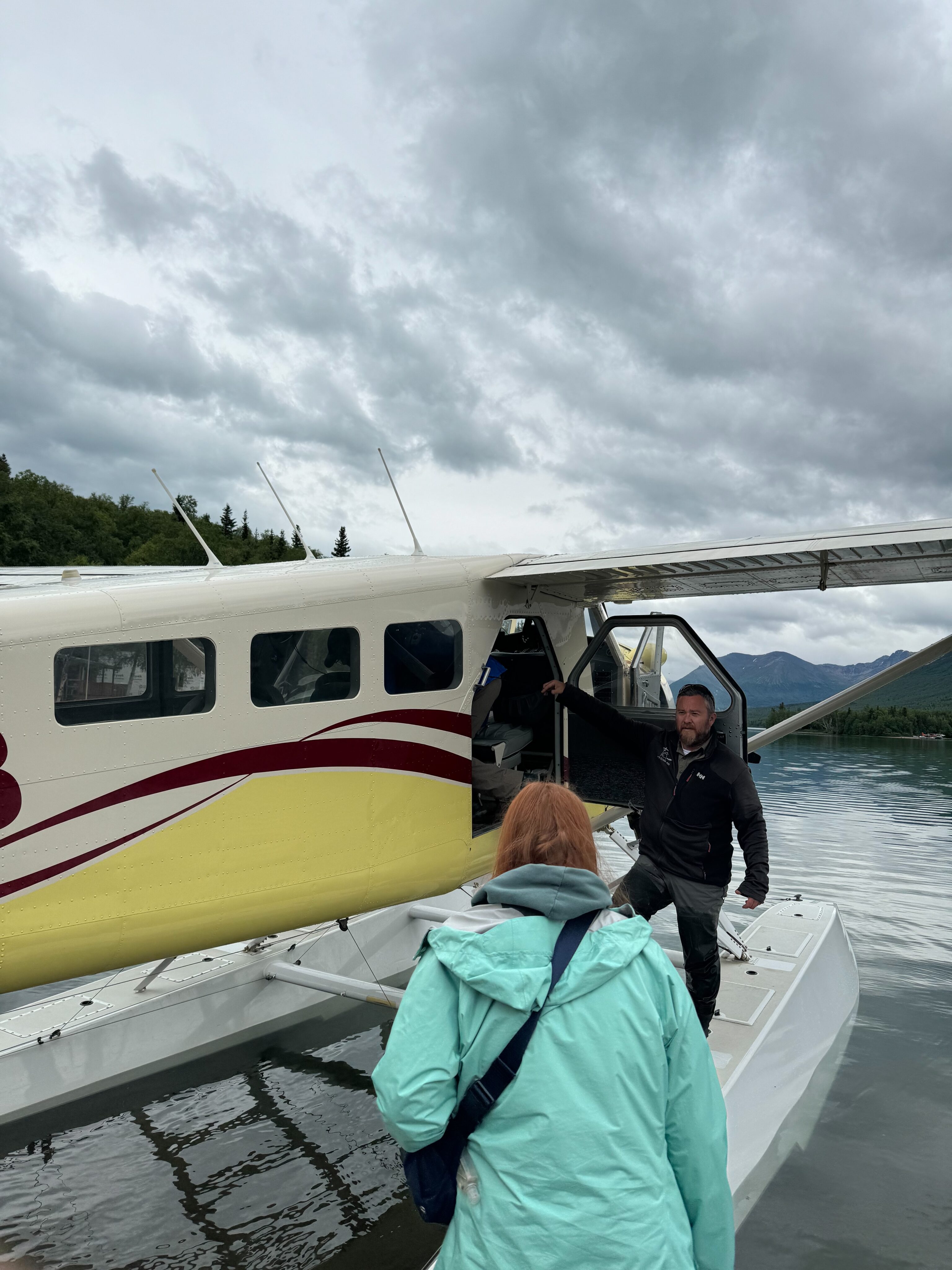 Cameron getting into the Lake Clark Air - de Havilland Beaver. On the shores of Lake Clark, with clouds overhead. 