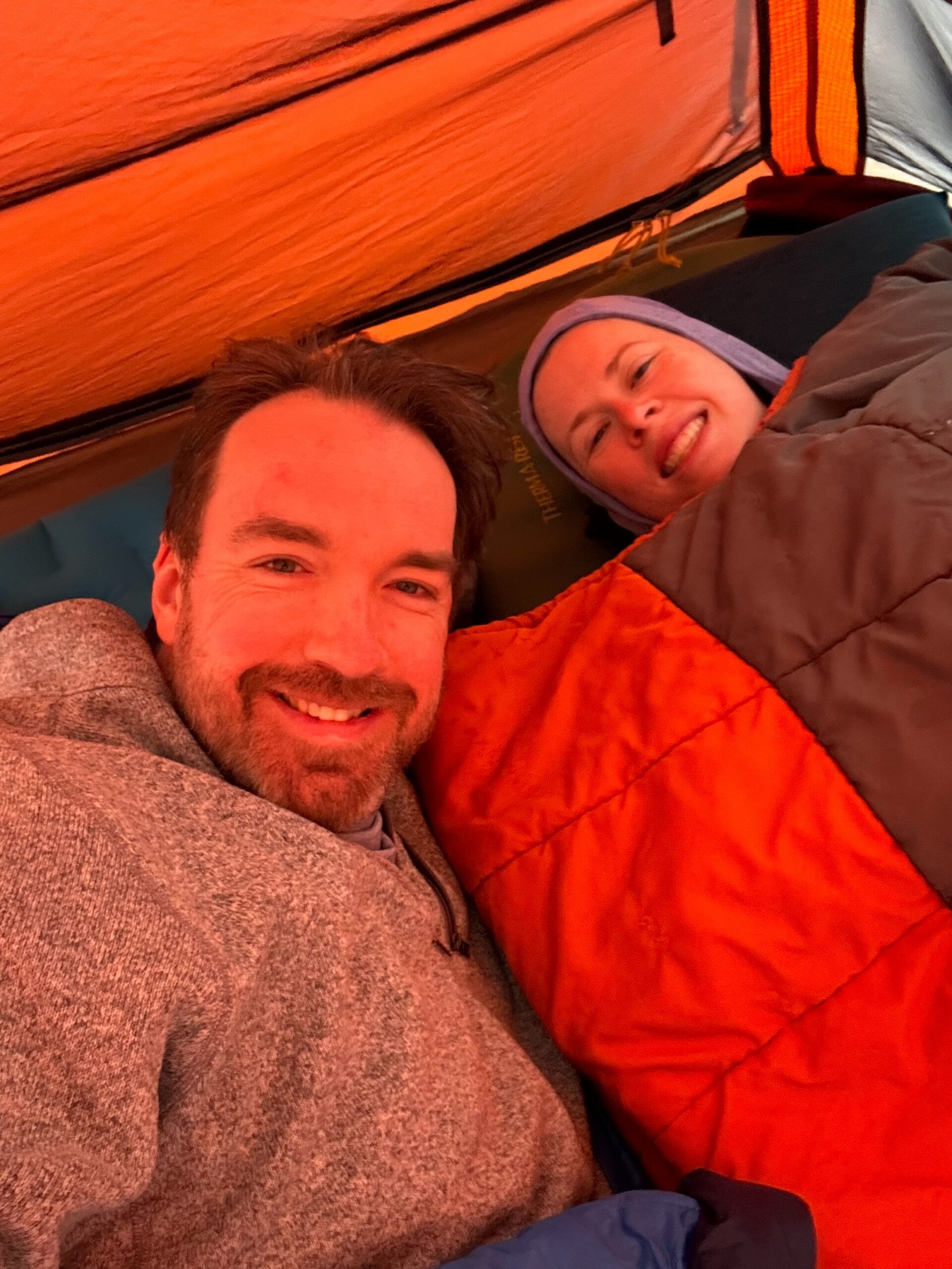 Cat and myself inside our tent, both in sleeping bags looking up at the camera.