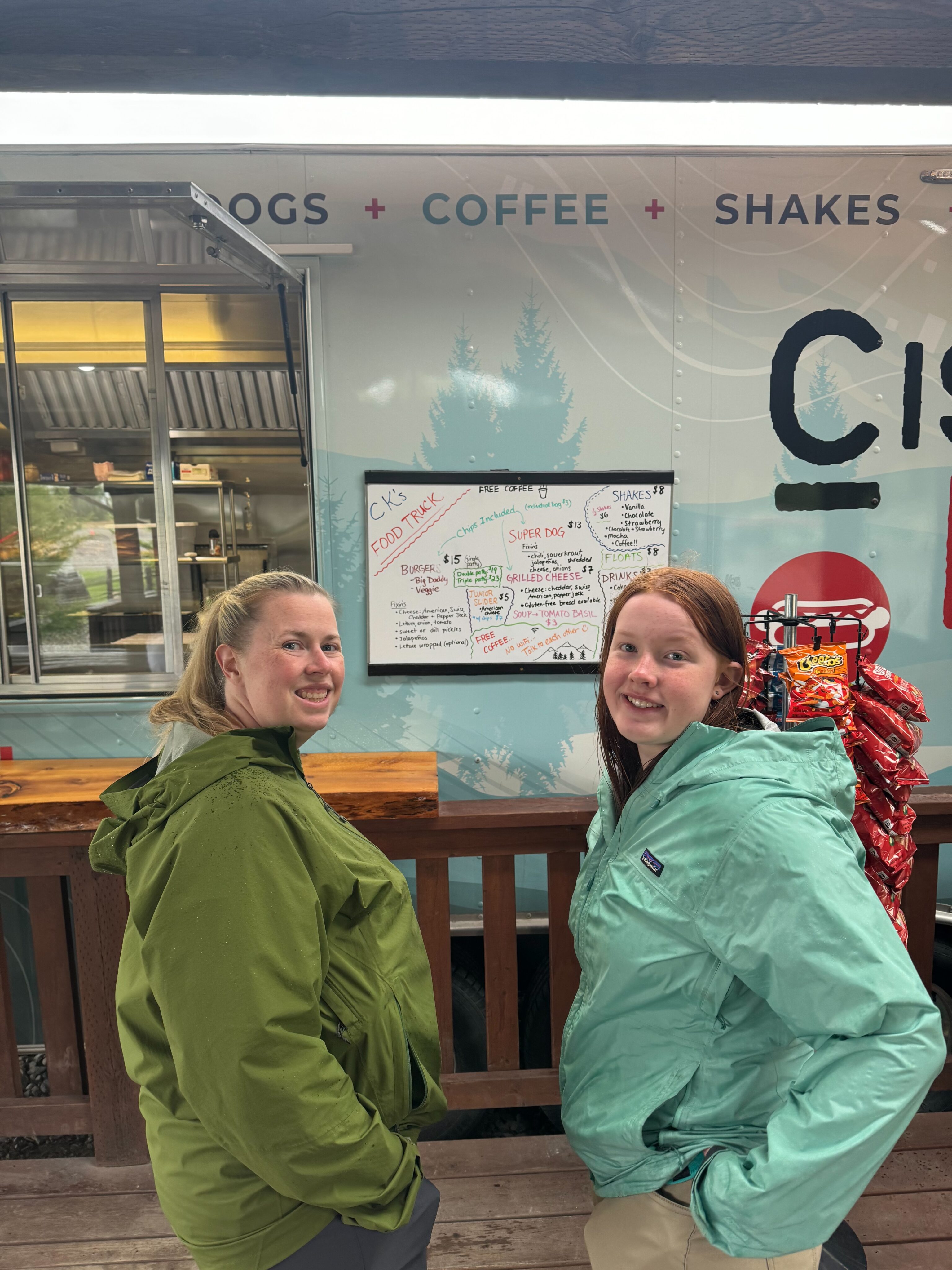 Cat and Cameron sand for photo in front of the food truck in Port Alsworth. Both wearing raincoats.