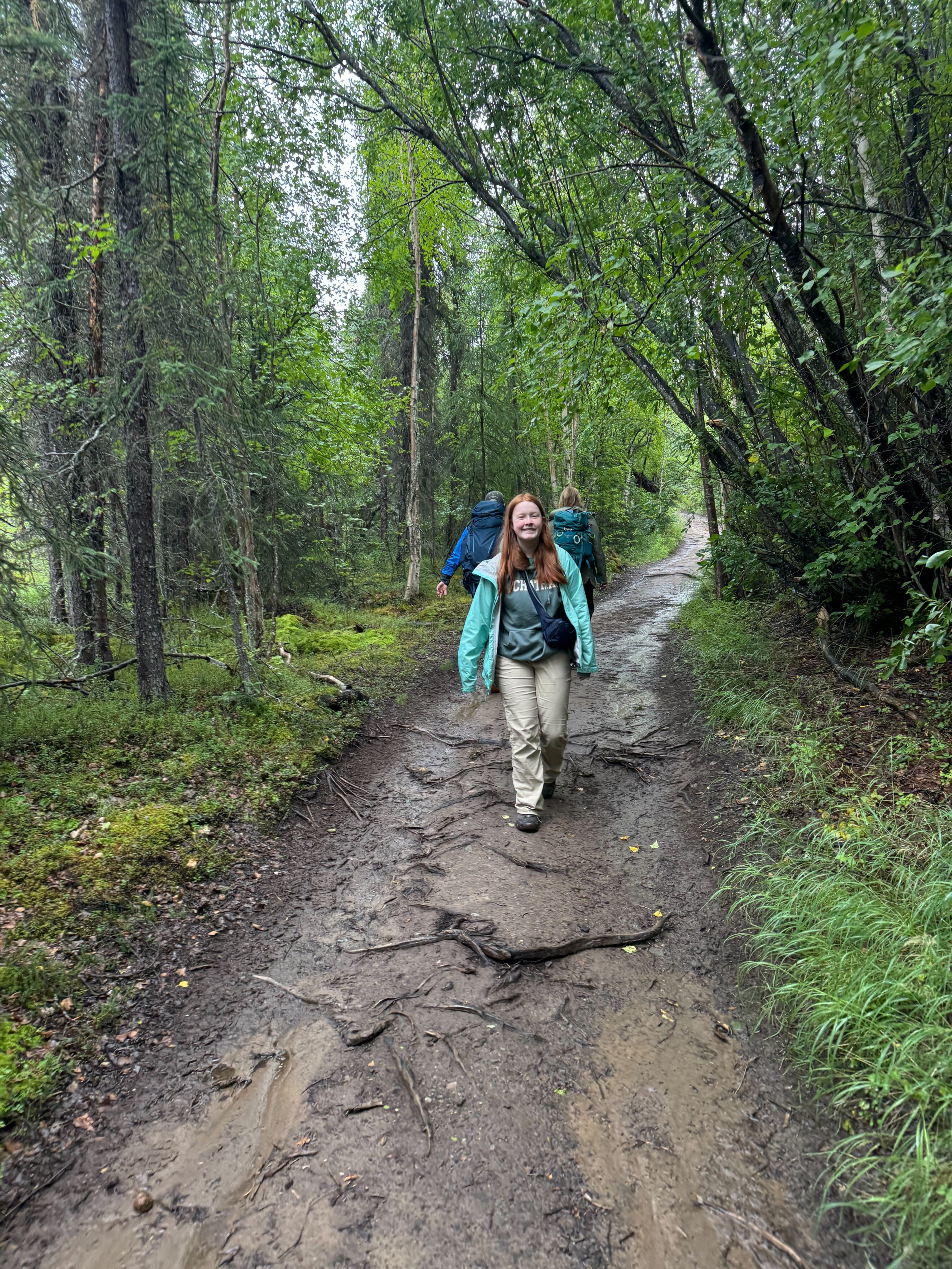 Cameron walking through the woods in the rain on her way to Tanalian Falls. 