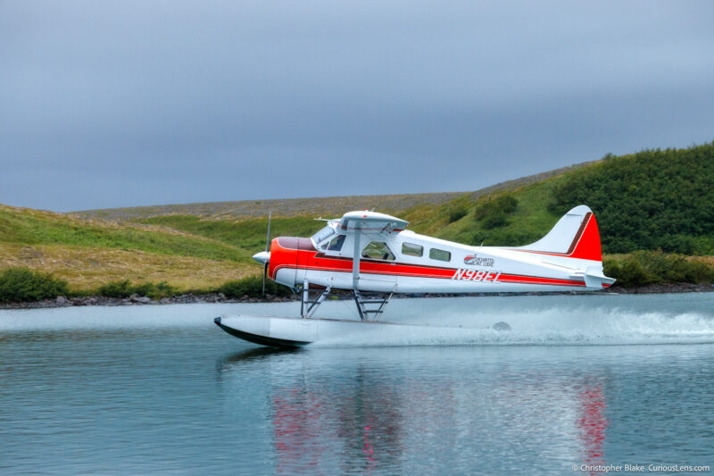 Float plane taking off from Crosswinds Lake in Katmai National Park, Alaska, showcasing remote wilderness air travel and adventure.