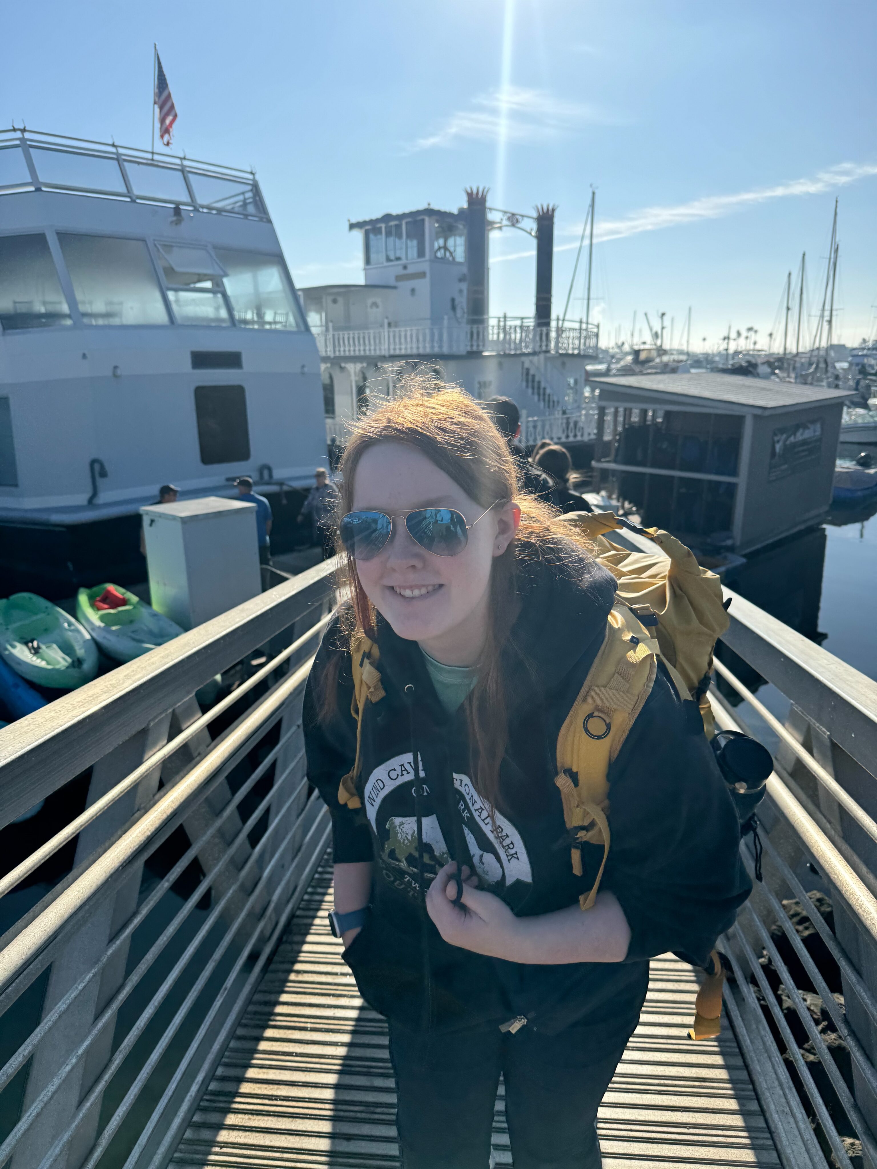 Cameron walking on a dock boarding a boat to the Channel Islands. wearing a Death Valley sweatshirt and sunglasses. 