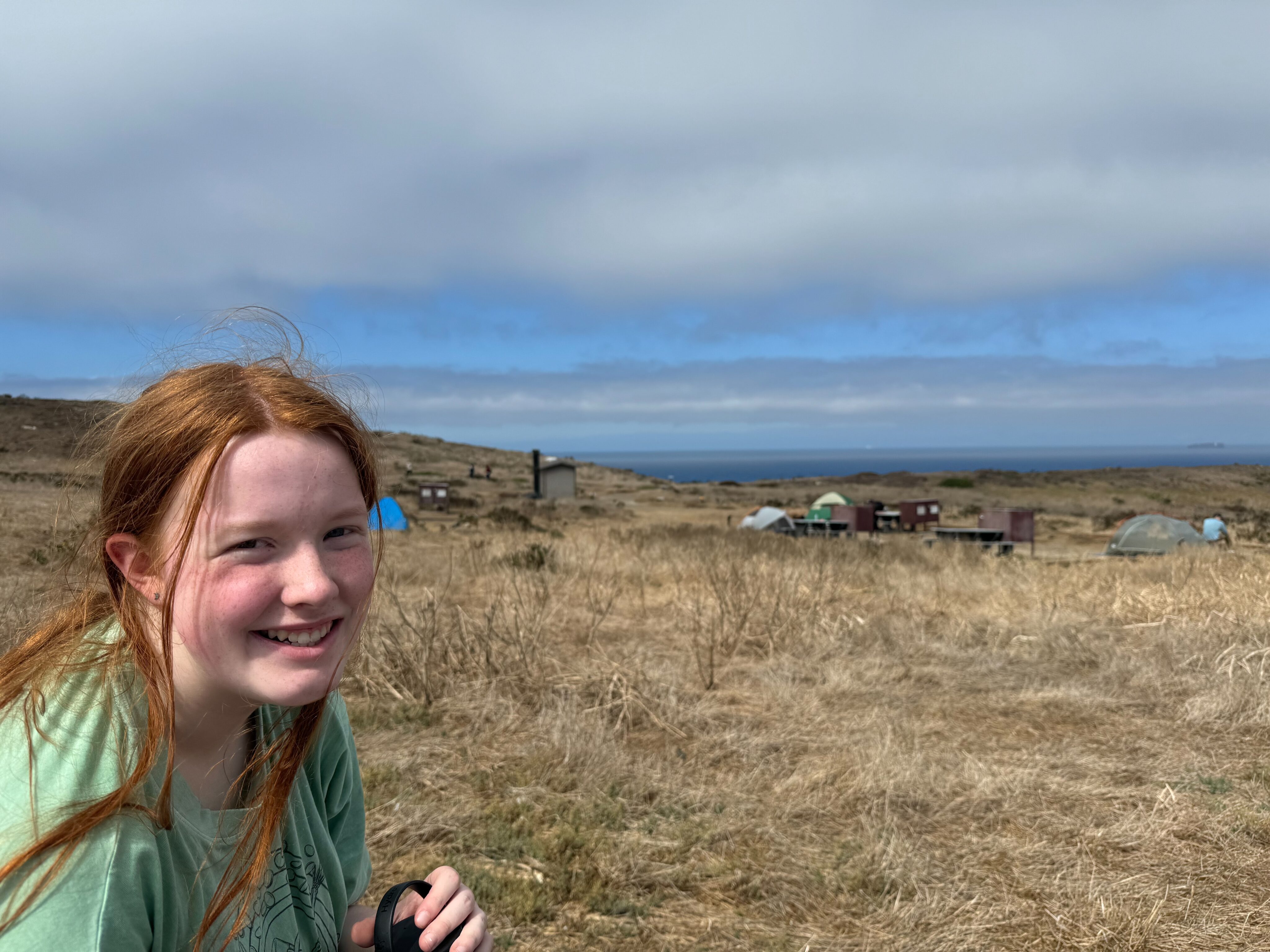 Cameron with her red hair blowing in the wind, all smiles as she sits at the table and has lunch at the campsite in Anacapa Island.