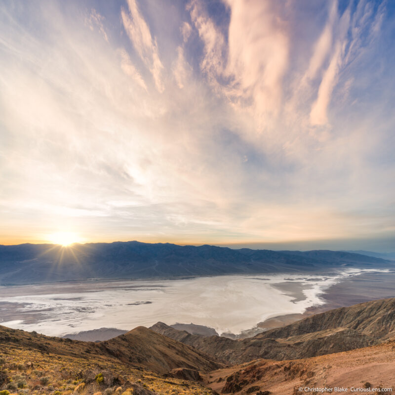 Sunset at Dante's View with a sunstar effect as the sun sets behind the Panamint Mountains, overlooking Badwater Basin and its expansive salt flats.