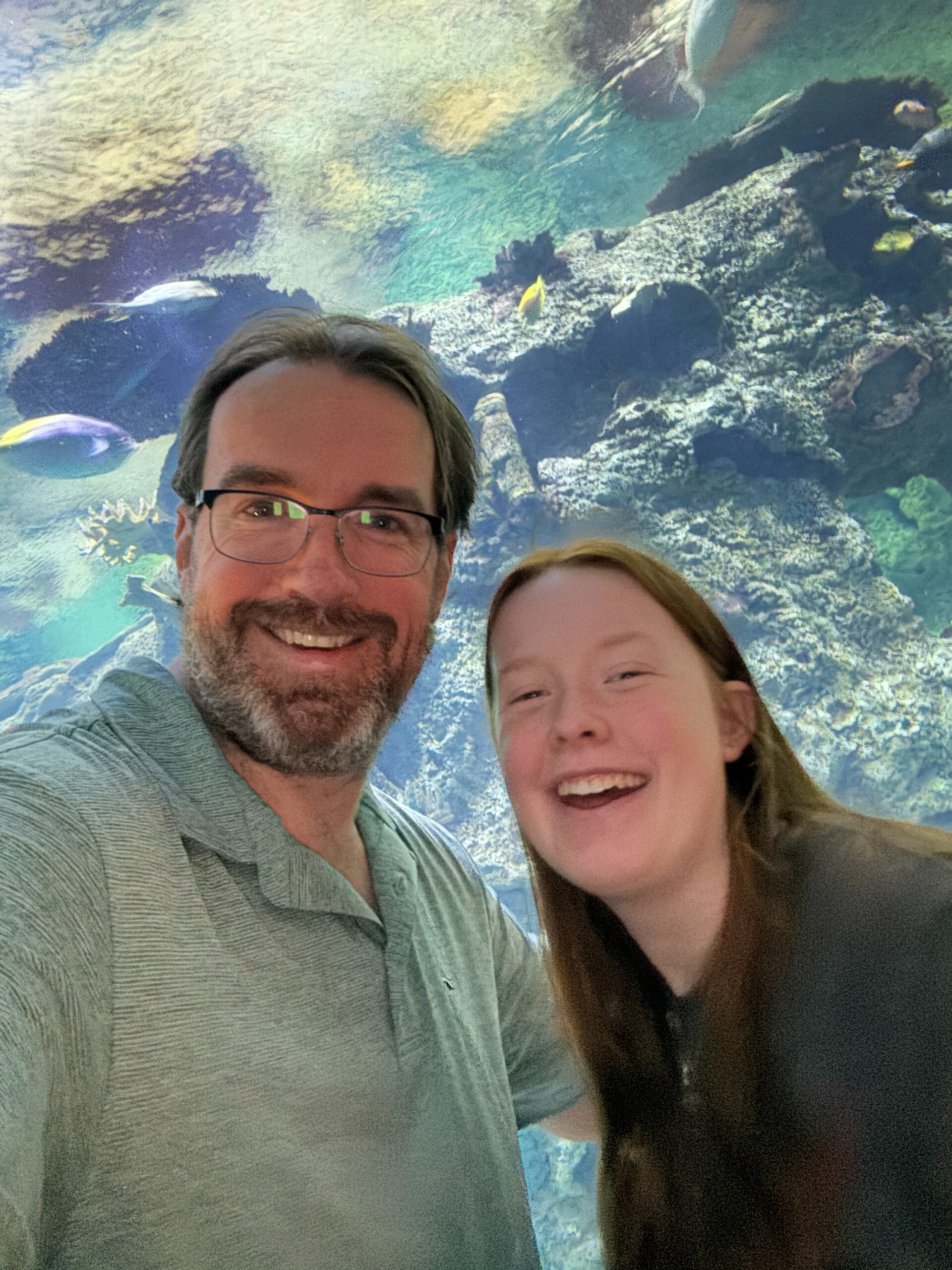 Chris and Cameron smiling in front of a massive fish tank.