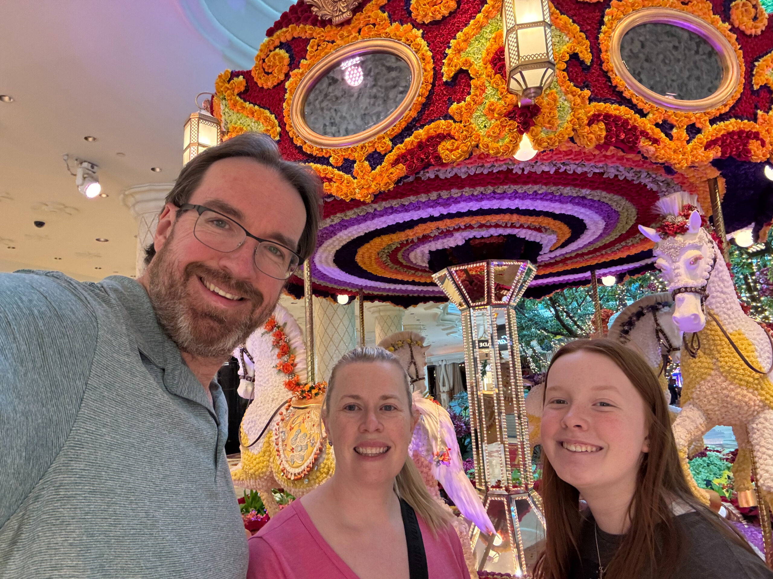 Chris, Cami and Cat in the atrium at The Wynn standing in front of the Carousel made of flowers. 