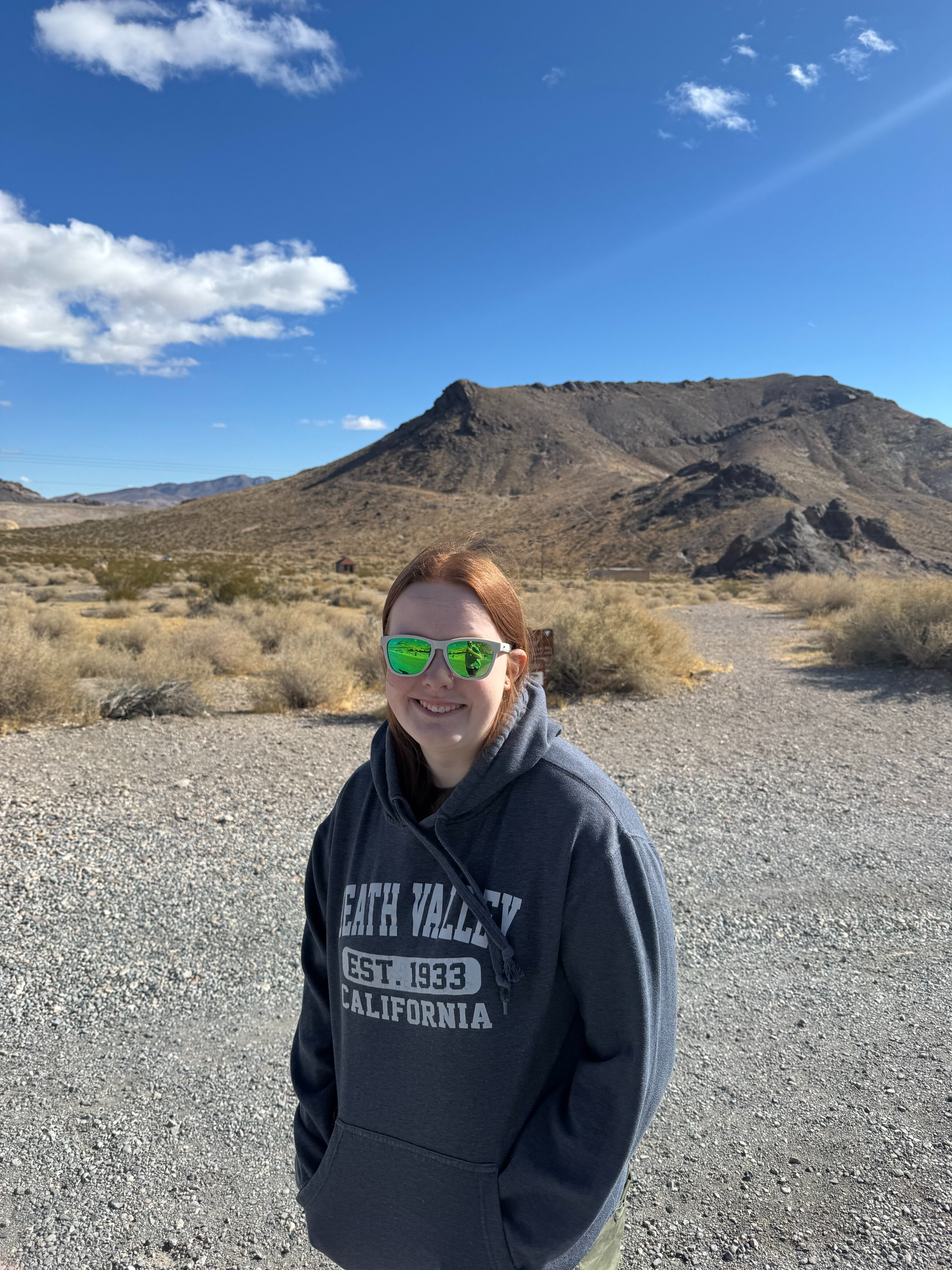 Cameron wearing a Death Valley Sweatshirt, standing in the desert in Death Valley.