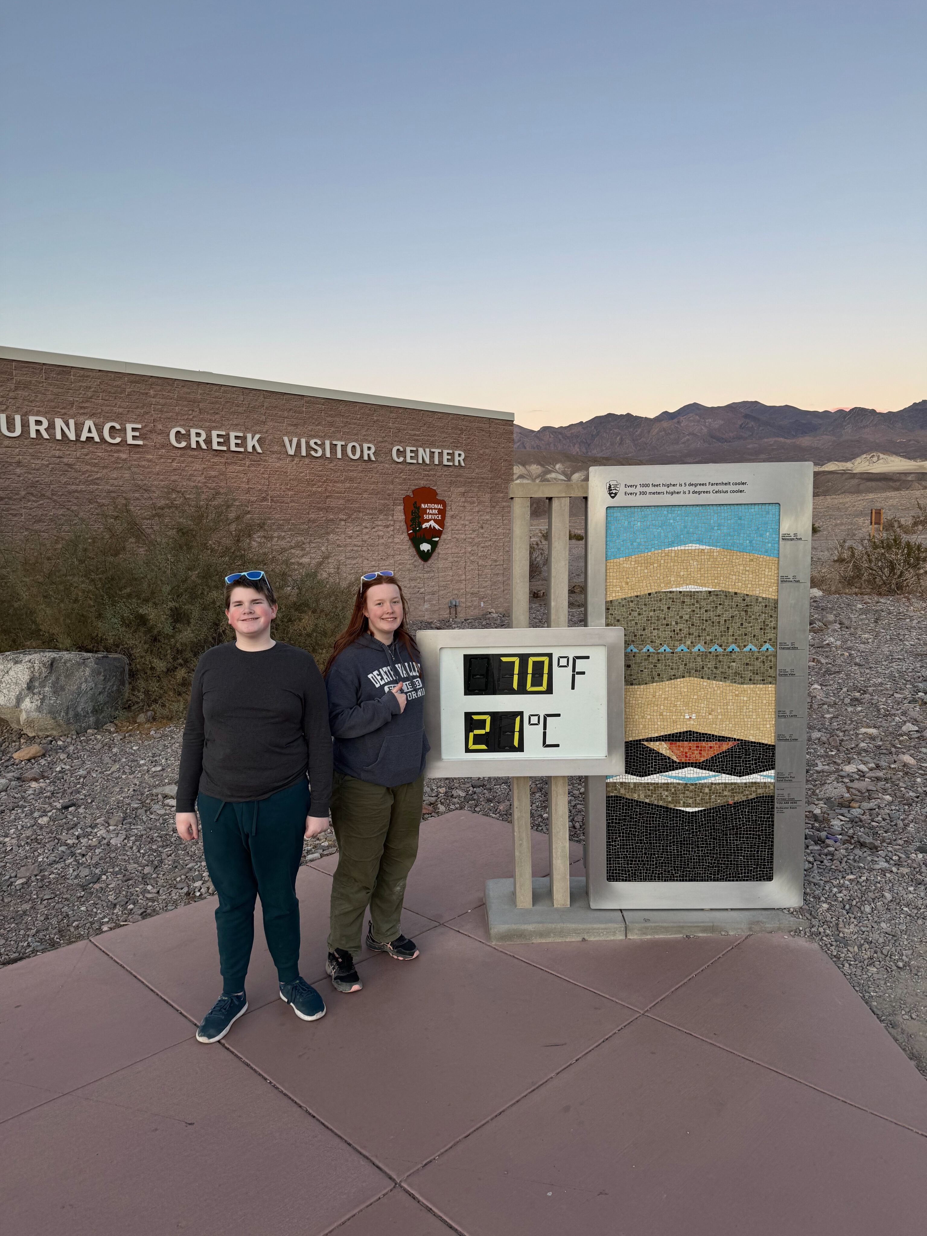 Cameron and Collin standing in front of the temperature sign at the Furnace Creek Visitors Center. 