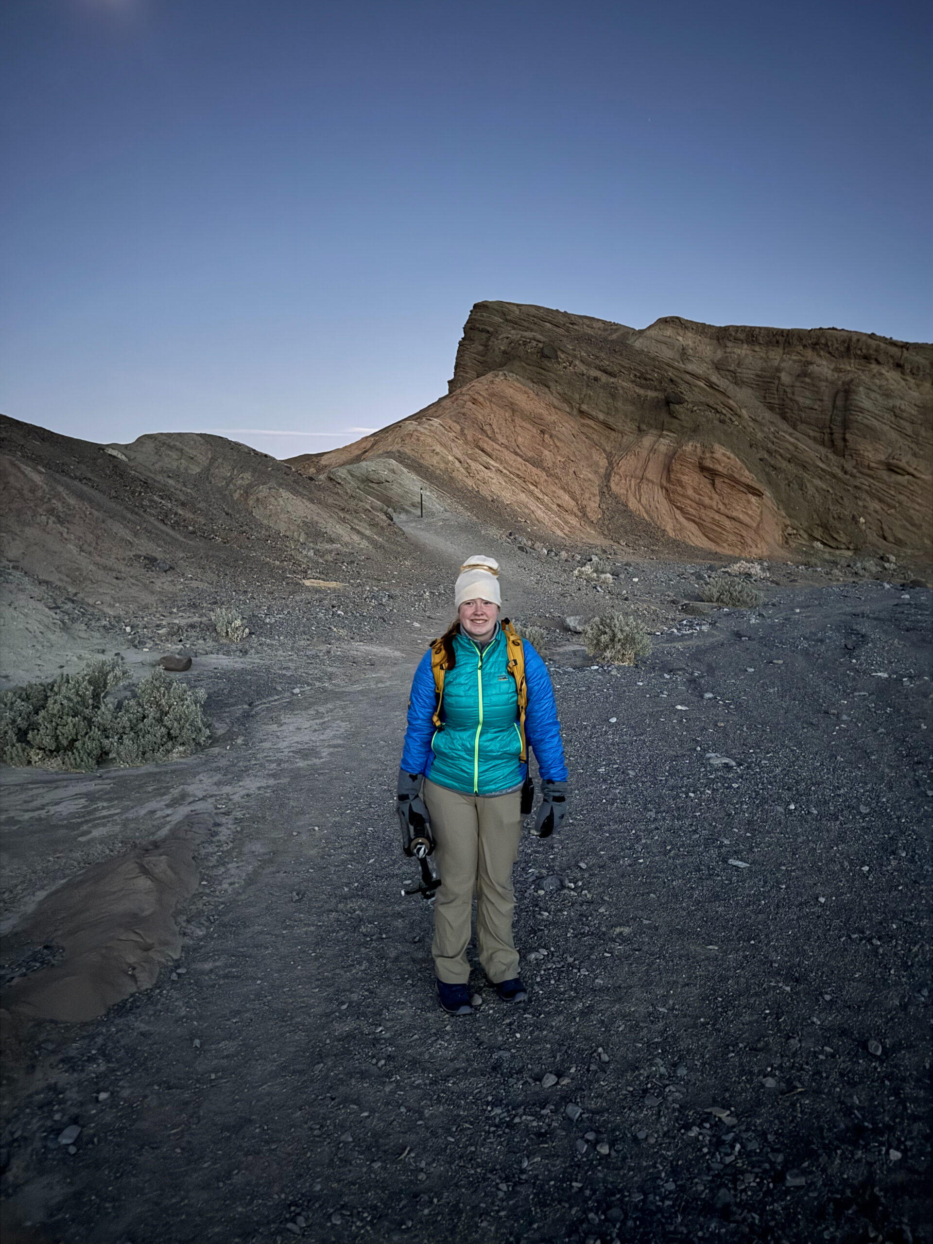 Cameron in her jacket, hat and gloves standing in the dark getting ready to do the hike near Zabriskie Point in Death Valley.