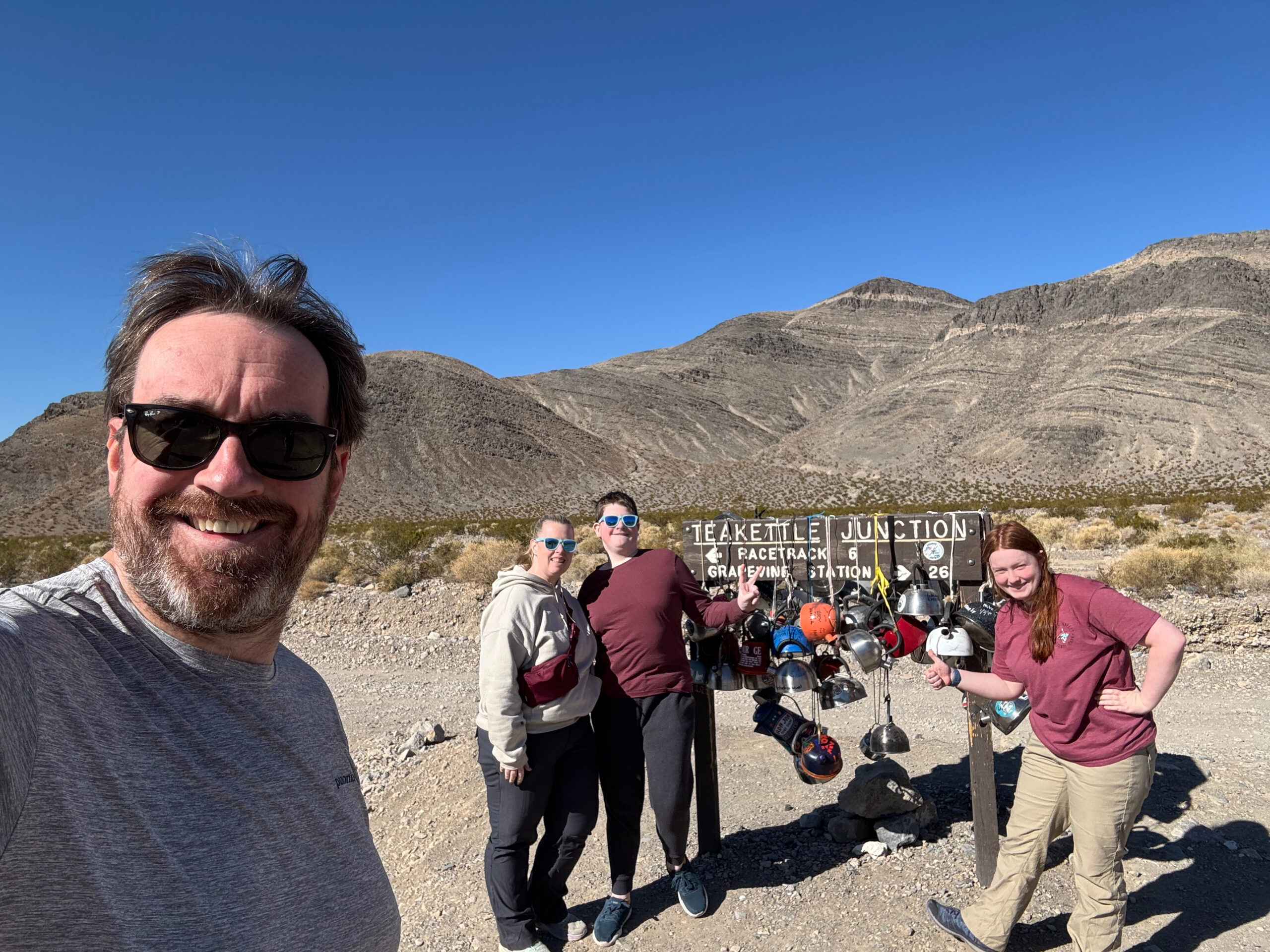 Chris, Cami, Collin, and Cat standing in front of the sign for Teakettle Junction in Death Valley.