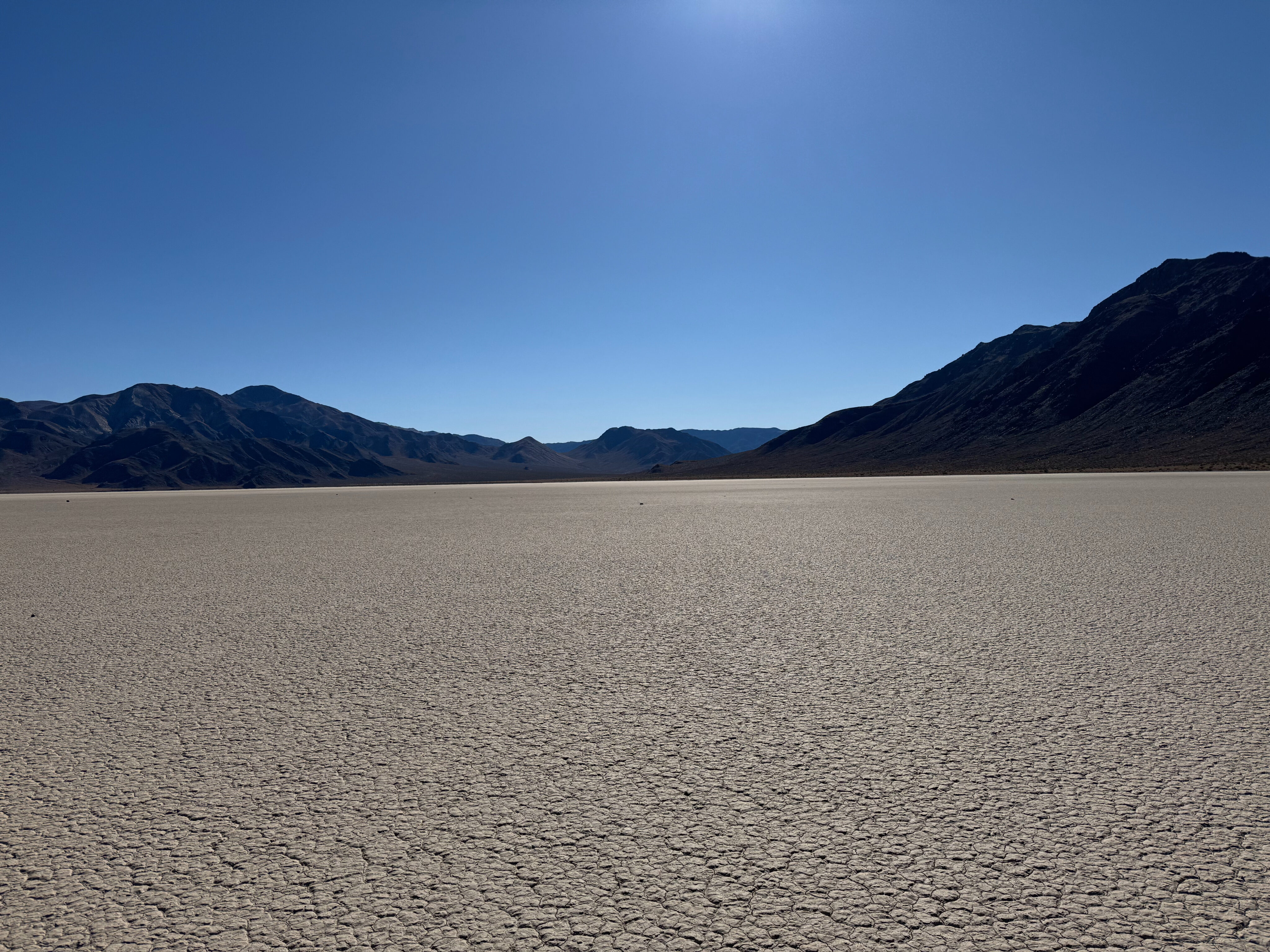 A wide view of the Racetrack in Death Valley on a bright blue sky afternoon. 