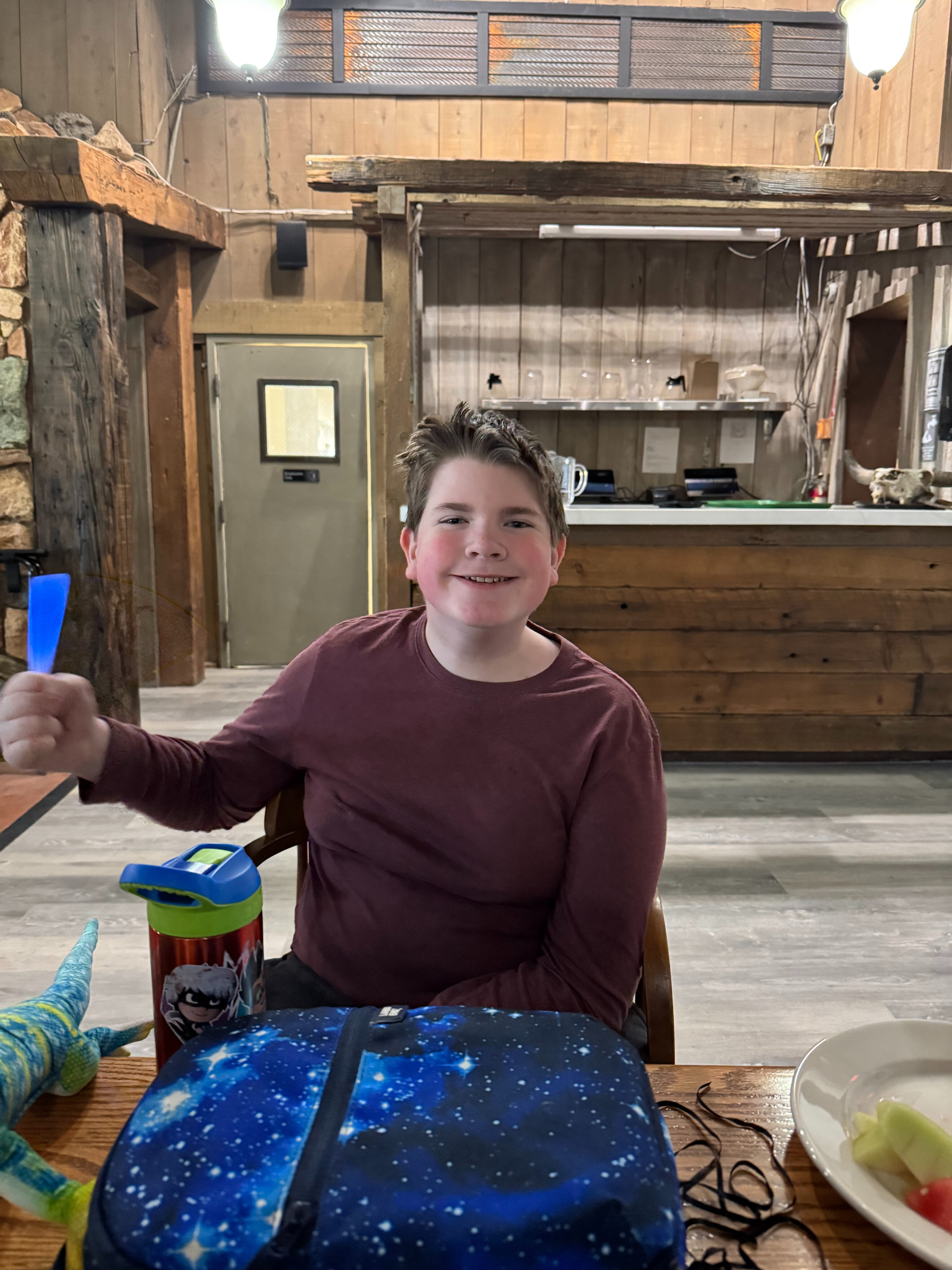 Collin sitting in the dinning room with his lunch box and a big smile at Stovepipe Wells. 