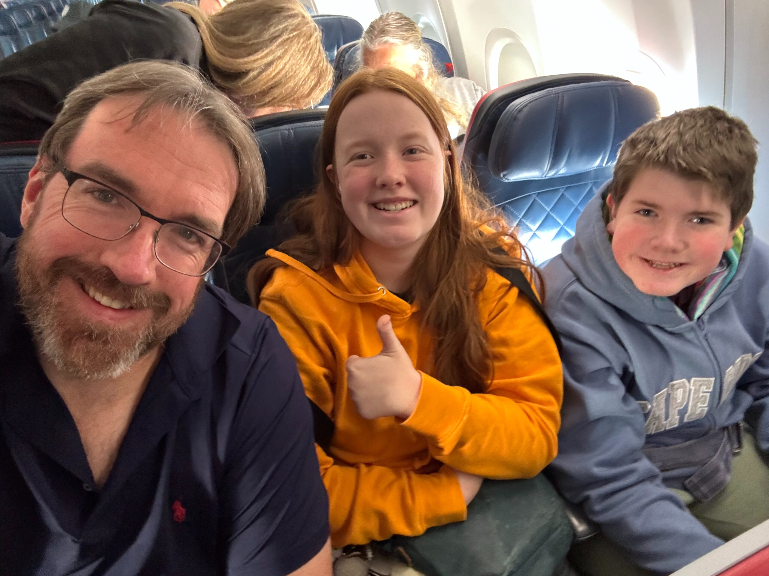 Chris, Cami and Collin all smiles sitting on the airplane. 