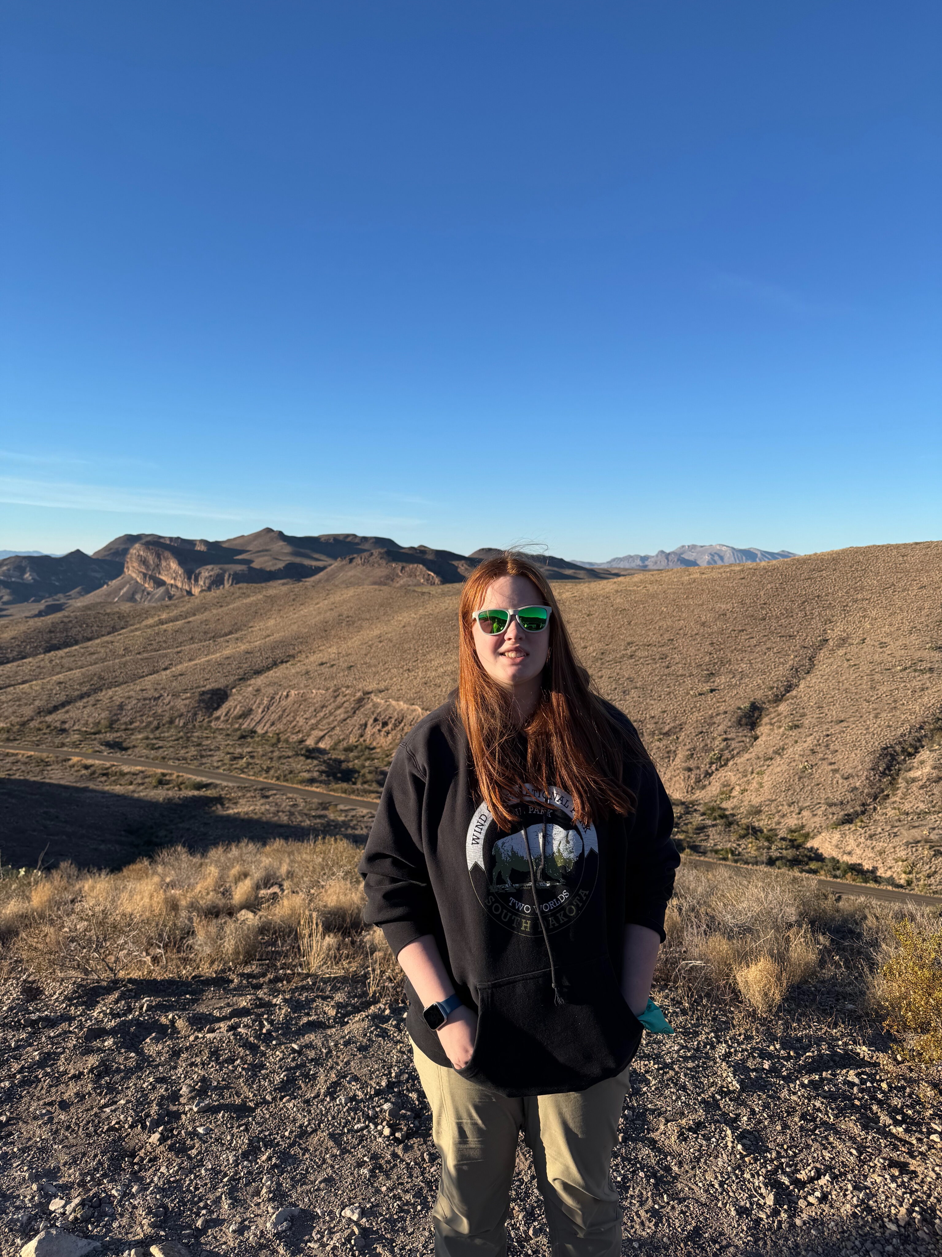 Cameron wearing sunglasses and a hoodie standing at the Sotol Vista Overlook.