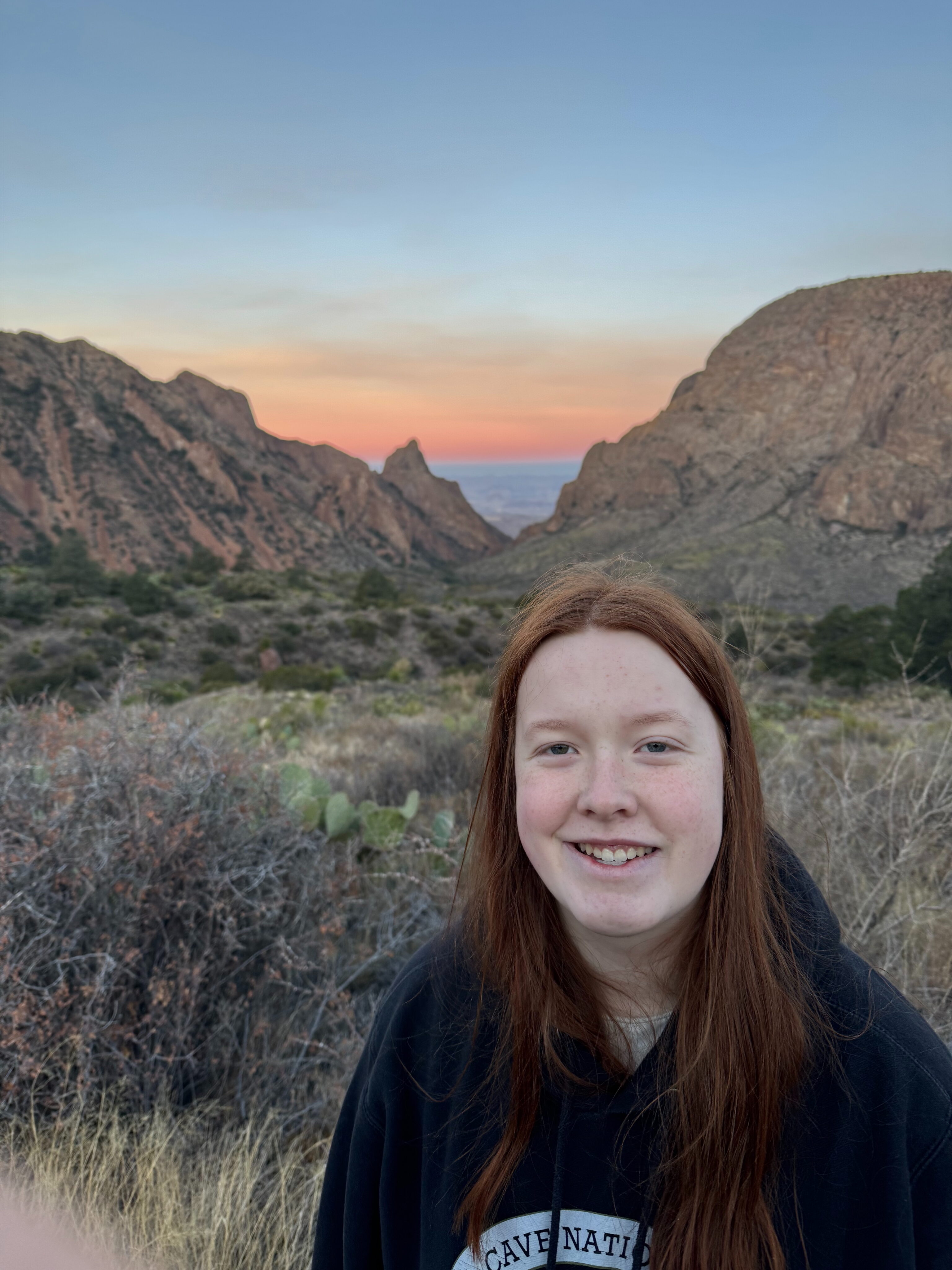 Cameron standing in the near dark at the Window Overlook in the Chisos Valley taken just before sunrise with the sky turning red.